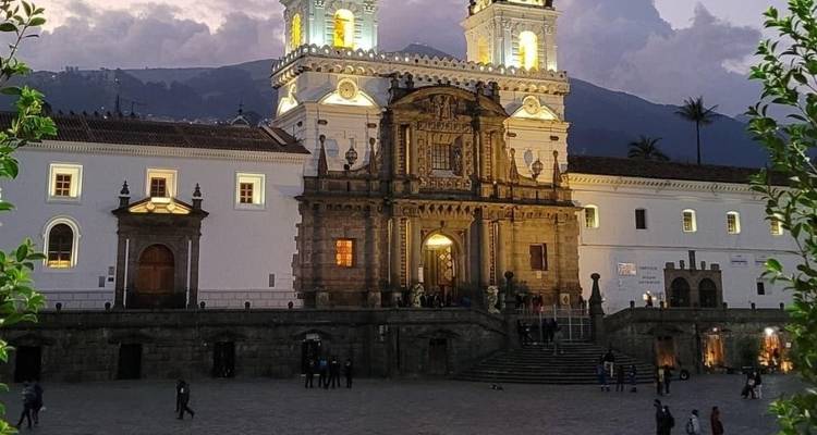 Bâtiment historique illuminé au crépuscule avec des gens qui marchent devant.