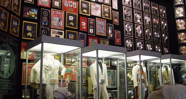Objets de collection d'Elvis exposés dans un musée avec un visiteur présent.