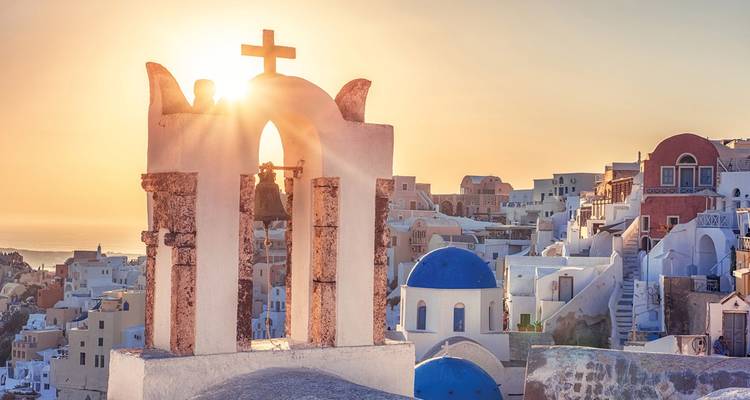 Edificios tradicionales y una iglesia con una puesta de sol en Santorini.