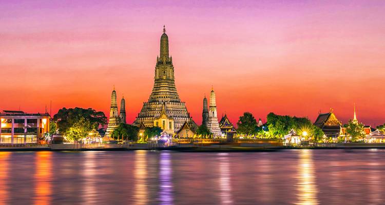 Temple Wat arun au coucher du soleil avec reflet sur l'eau.