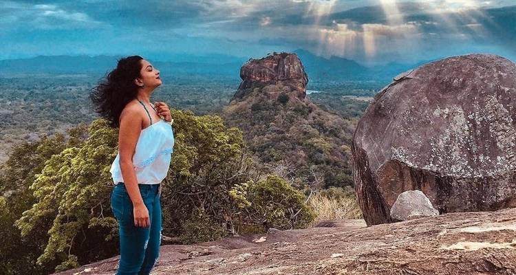 Mujer posando con la formación rocosa de Sigiriya en el fondo.