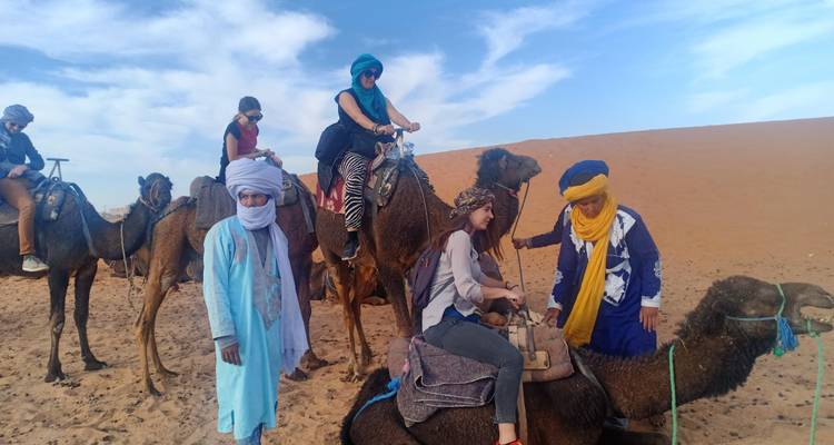 Tourists riding camels with local guides in the desert.