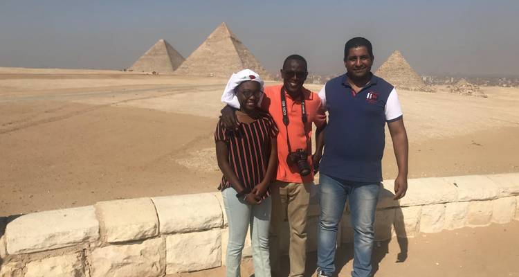 Drie mensen poseren met piramides op de achtergrond.