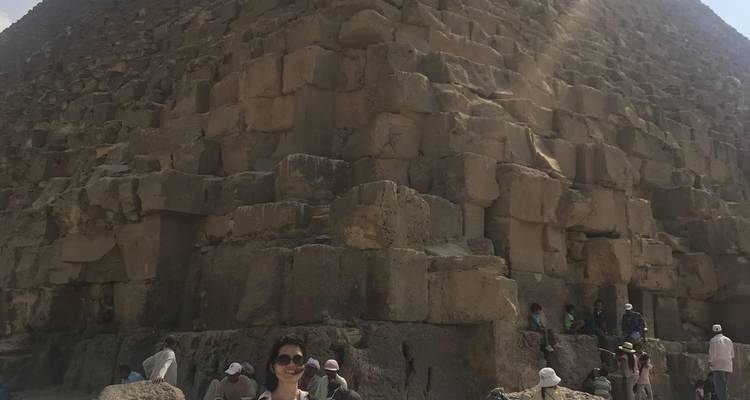 Persoon bij de voet van een grote piramide met stenen blokken.
