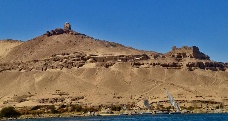 Zeilboten op een rivier met woestijnheuvel op de achtergrond.