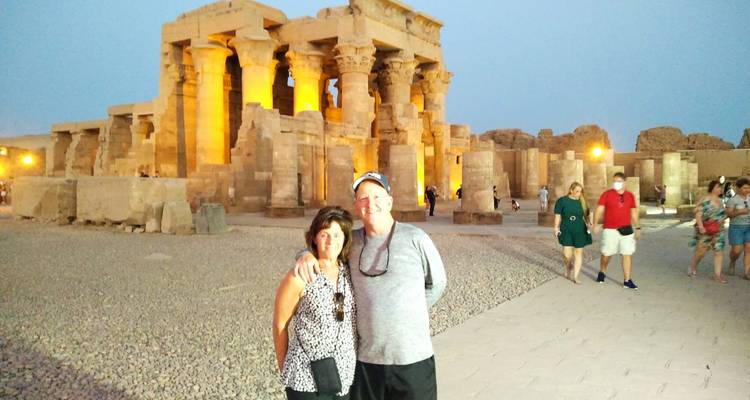 Paar posiert vor einem beleuchteten antiken Tempel in der Abenddämmerung.