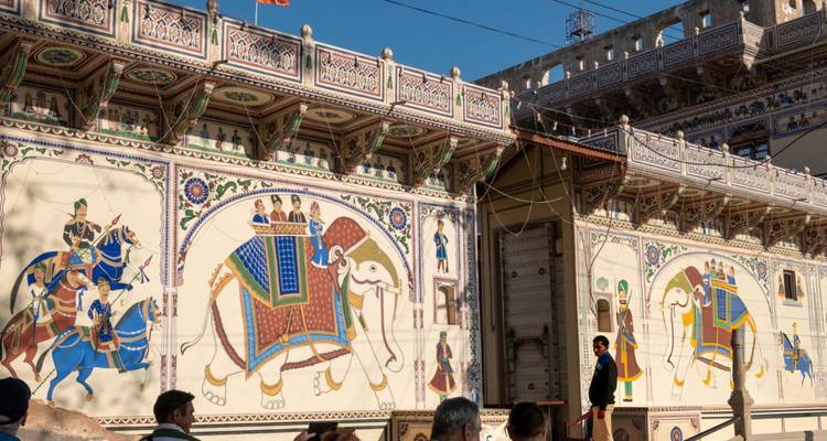 Painted wall of a haveli with people observing.