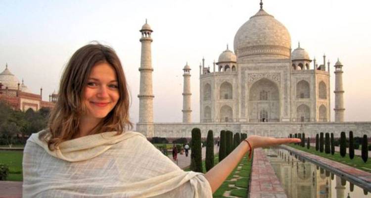 Woman posing with the Taj Mahal in the background.