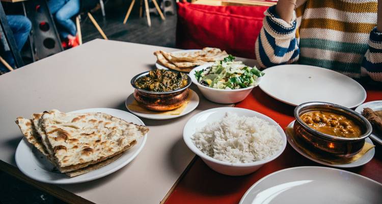 Tafel met verschillende Indiase gerechten, inclusief rijst en brood.