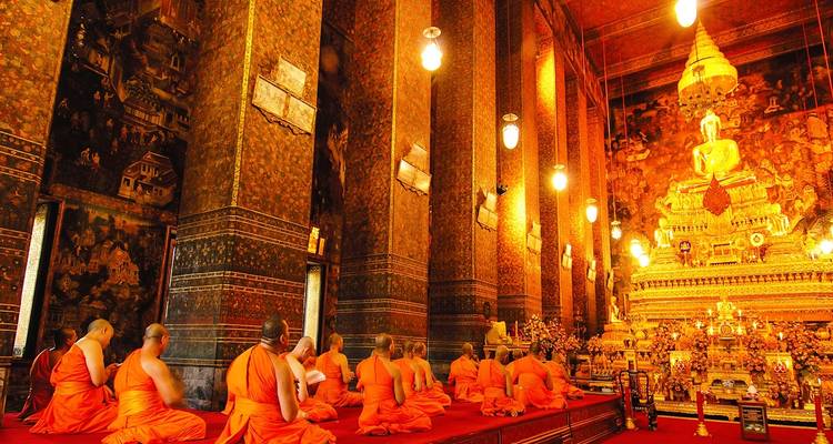 Monjes en un templo ornamentado realizando oraciones.