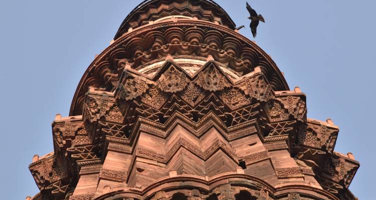 Close-up of intricately carved tower with bird in view.