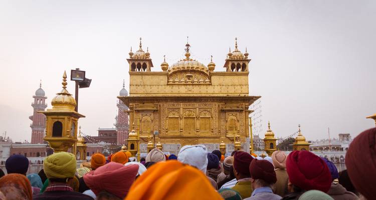 Golden temple with crowd of people, prominent architectural design.