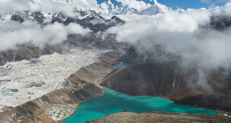 Luftaufnahme eines türkisfarbenen Sees in einer Bergregion.