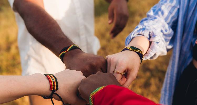 Un grupo de individuos mostrando unidad con puños unidos y pulseras tradicionales.