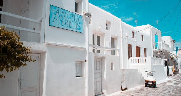 Callejón blanco con acentos azules y un letrero que dice Mykonos