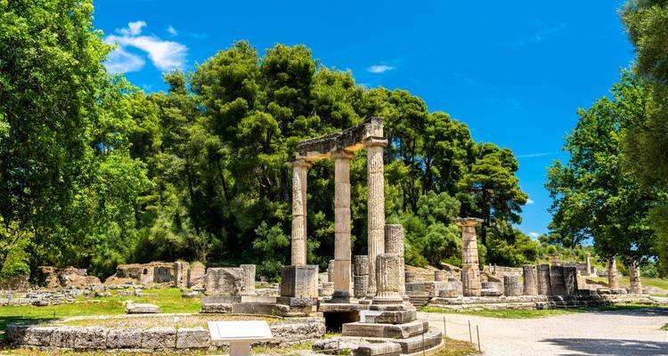 Ruinas antiguas con columnas rodeadas de exuberante vegetación.