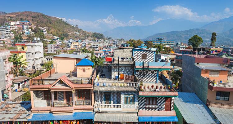 Paysage urbain avec collines et montagnes lointaines.