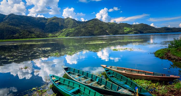 Des bateaux en bois sur un lac serein avec des montagnes.