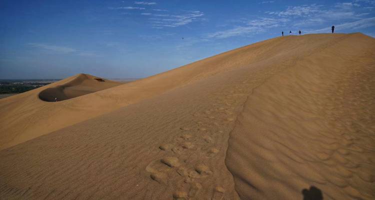 Des gens qui marchent sur une grande dune de sable.