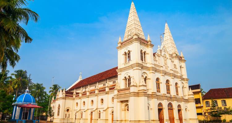 Basílica elegante de dos torres blancas gemelas recortada contra un brillante cielo azul de Kerala.