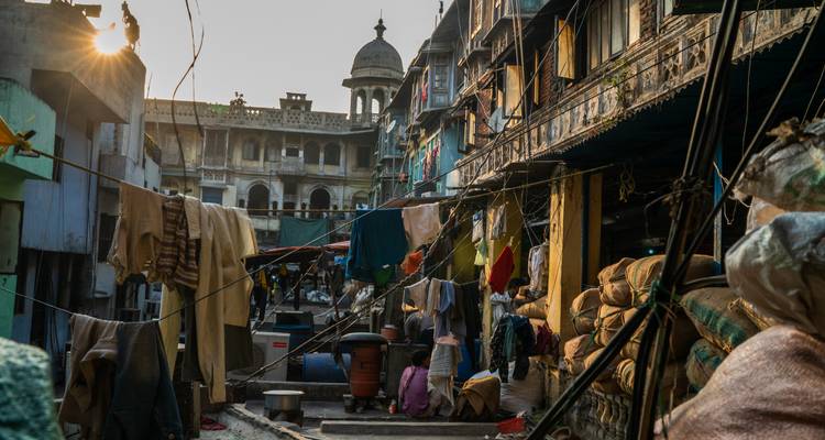 La lumière du soleil filtre à travers un dédale de linge suspendu et de marchandises empilées dans une ruelle étroite du Vieux Delhi.