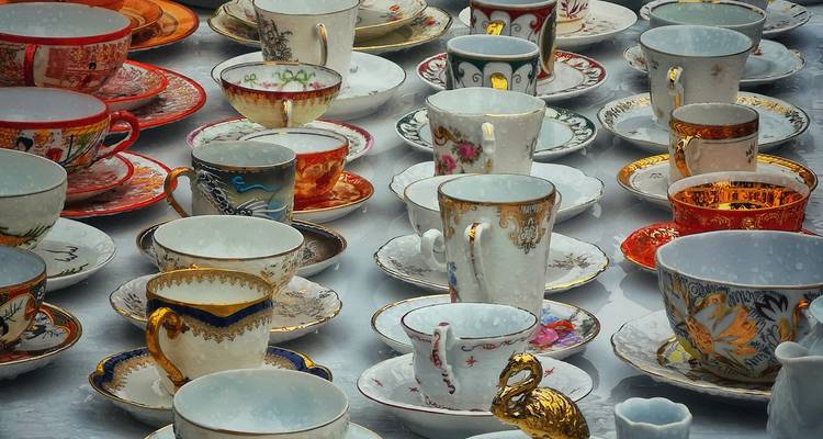 An assortment of ornate teacups and saucers on display.