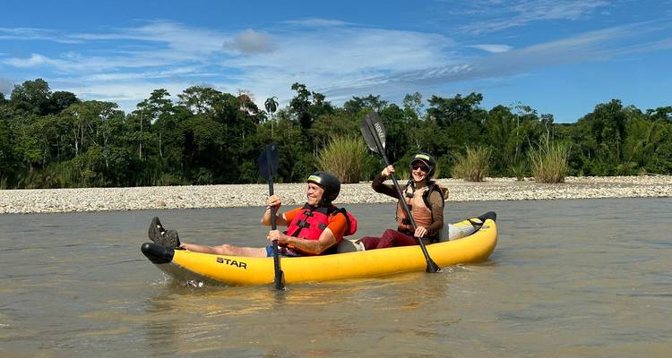 Two people celebrating in a kayak with paddles raised.