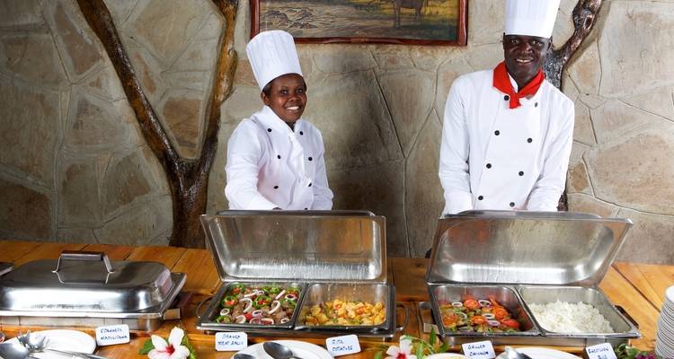 Two chefs in uniform standing behind a buffet spread.