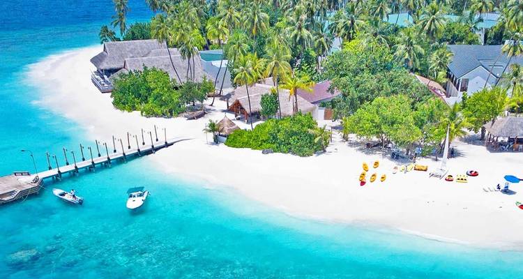 Vue aérienne d'un complexe hôtelier de plage avec des eaux turquoise et des palmiers.