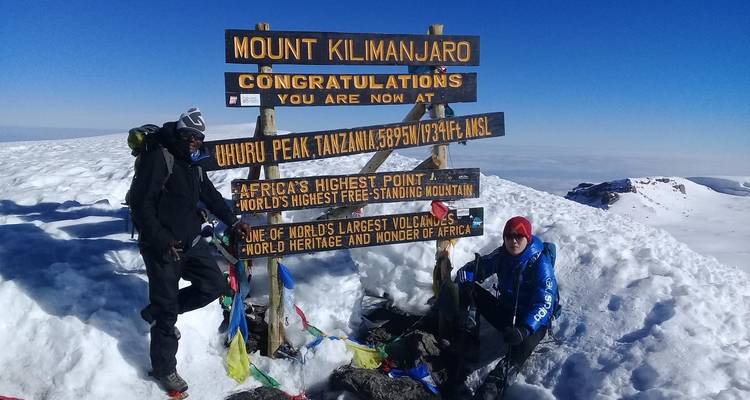 Excursionistas posaron junto a un letrero de la cumbre del Monte Kilimanjaro en la nieve.