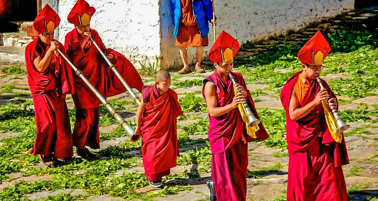 Monniken in traditionele kleding die lopen met lange hoorns.