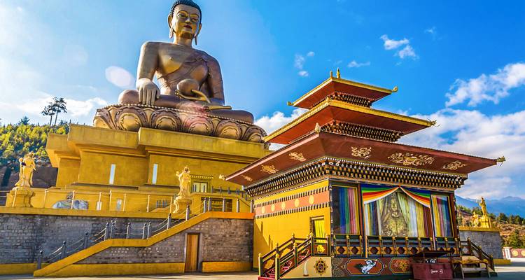 Statue des Buddha Dordenma mit umliegenden Strukturen an einem klaren Tag.