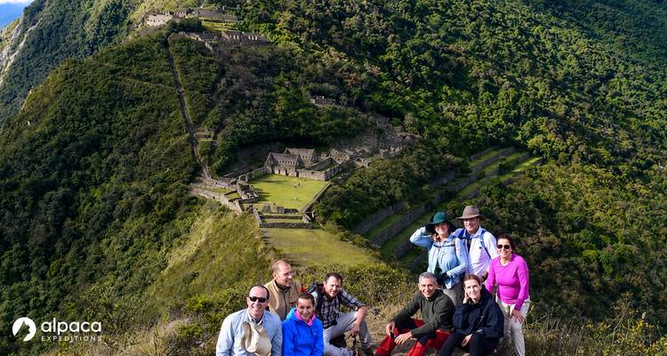 Hiking group with Alpaca Expeditions logo poses above Choquequirao ruins.
