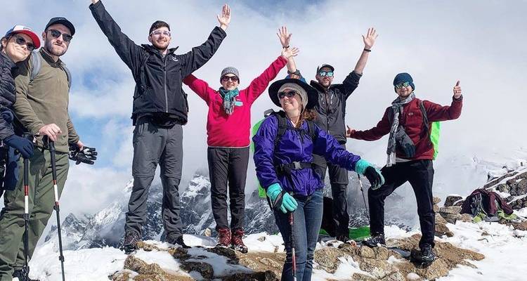 Grupo de personas posando alegremente en una montaña nevada.