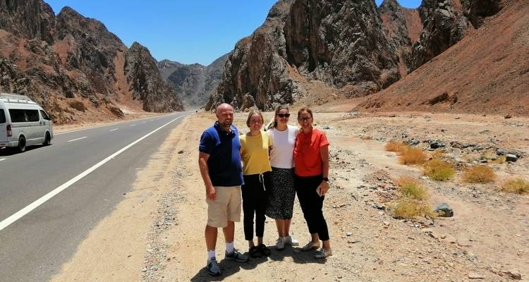 A group of people standing on a road with mountains in the background.