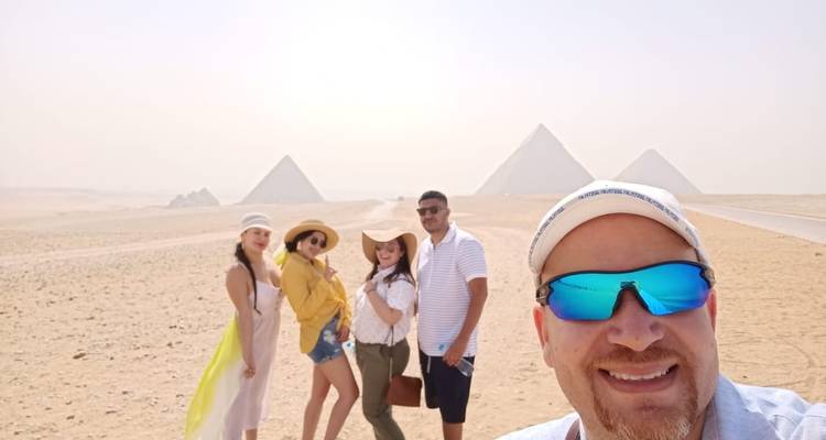 Groupe de personnes posant devant les Pyramides de Gizeh.