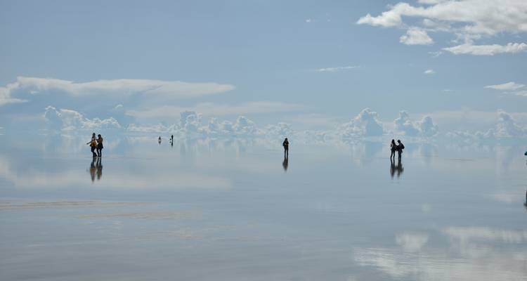 Los viajeros se reflejaban en la superficie inundada similar a un espejo del Salar de Uyuni bajo cielos llenos de nubes
