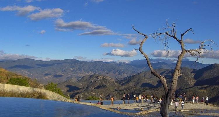 Piscine à débordement à Hierve el Agua surplombant les chaînes de montagnes lointaines sous un ciel bleu éclatant.