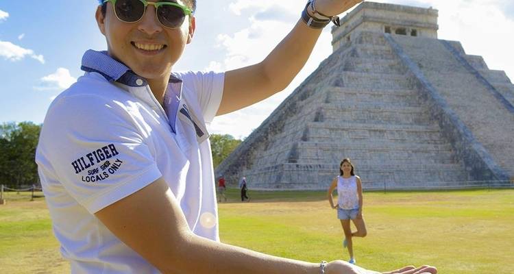 Un touriste pose de manière ludique en tenant la pyramide de Chichen Itza tandis qu'un ami se tient en arrière-plan.