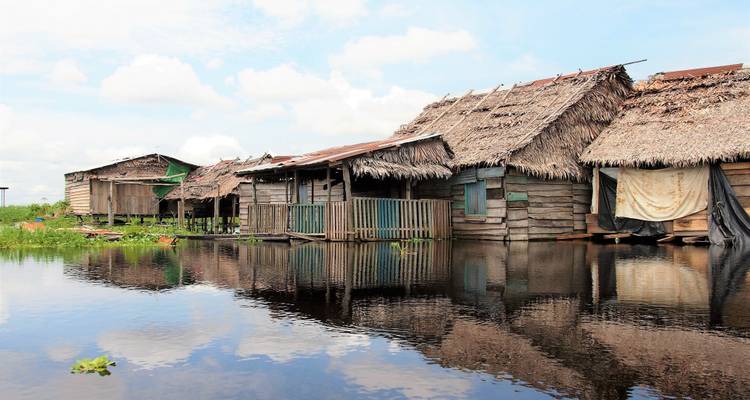 Casas de madera sobre pilotes junto al agua en una zona rural.