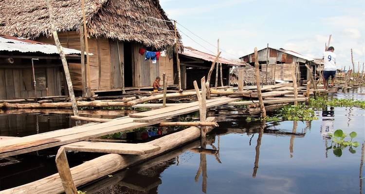 Pasarela de madera a través de pueblo parcialmente inundado.