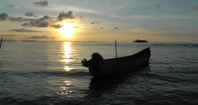 Silueta de un barco al atardecer sobre aguas tranquilas del mar.