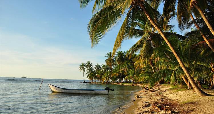 Plage tropicale avec un bateau amarré au rivage.