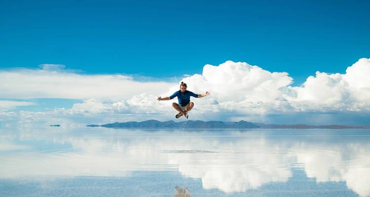 Persoon die in de lucht springt op het reflecterende oppervlak van de Uyuni Zoutvlakte.