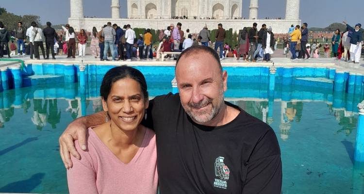 A couple sitting by a reflecting pool with the Taj Mahal in the background.