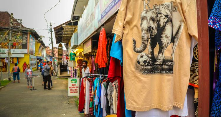 Straatmarkt met kleurrijke kleding en een T-shirt met een olifant erop.