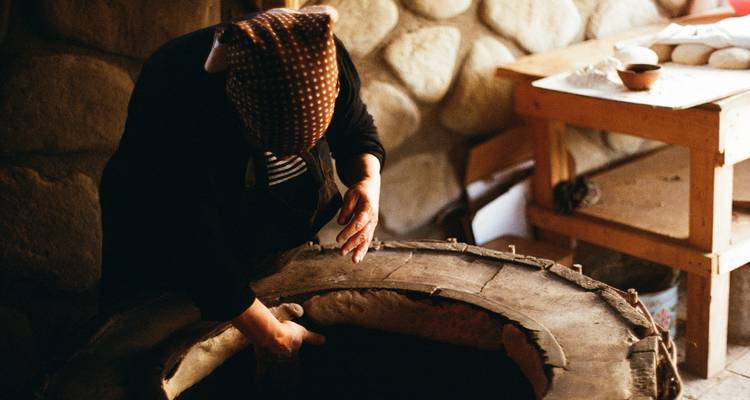 A person baking bread in a traditional stone oven.