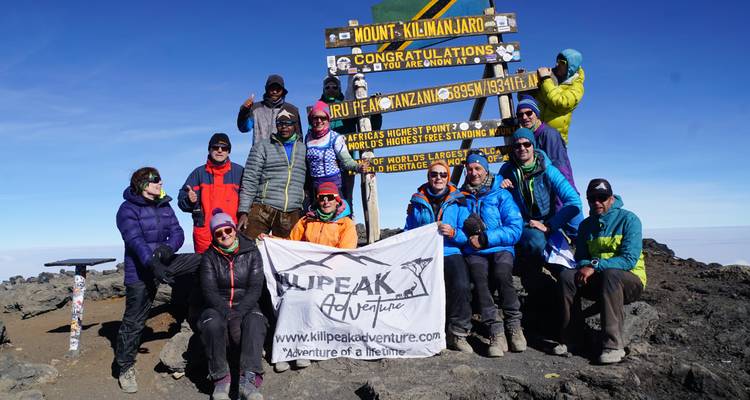 Group photo of people at the summit of Mount Kilimanjaro.