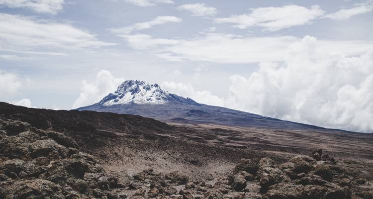 Premier plan rocheux avec le mont Kilimandjaro en arrière-plan.