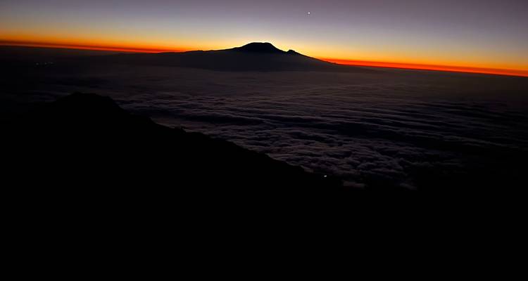 Silhouette d'une montagne avec un lever de soleil vibrant en arrière-plan.